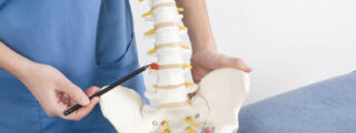 Fizjoterapeuta wskazujący na model kręgosłupa, podkreślający dysk międzykręgowy w kontekście edukacji na temat dyskopatii i zdrowia kręgosłupa.