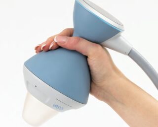 Głowica terapii falą uderzeniową umieszczona na stół terapeutycznym, przygotowana do zabiegu leczenia bólu w terapii fizykalnej.